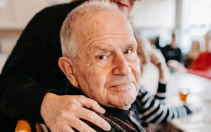 Ein Rentner schaut dich freundlich an