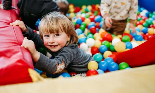 Glückliches Kind spielt im Bällebad mit anderen