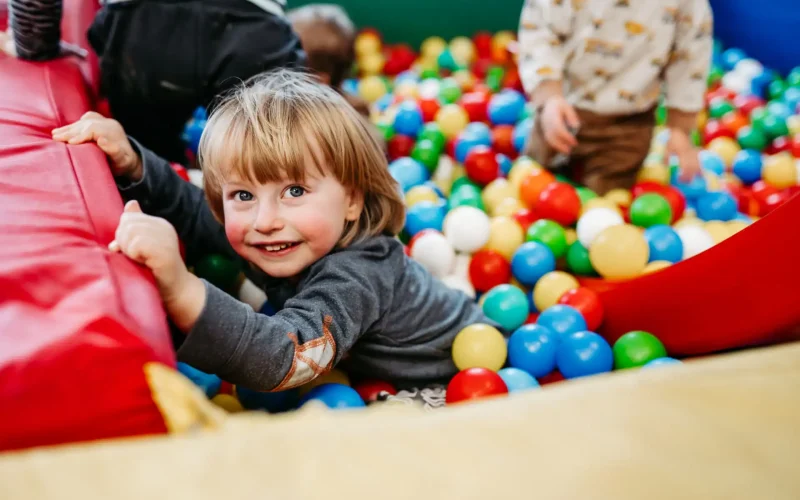 Glückliches Kind spielt im Bällebad mit anderen