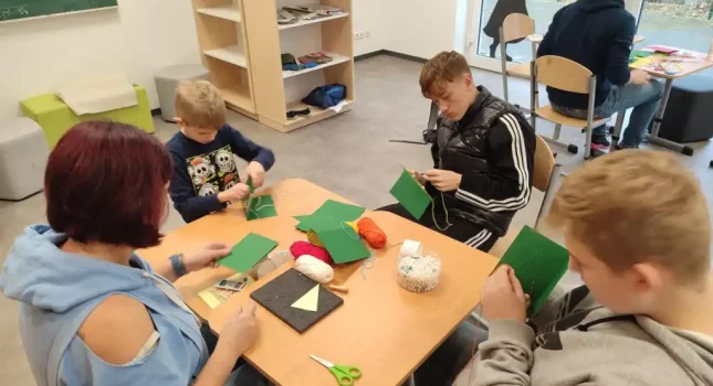 Jugendliche und Kinder basteln eine Karte