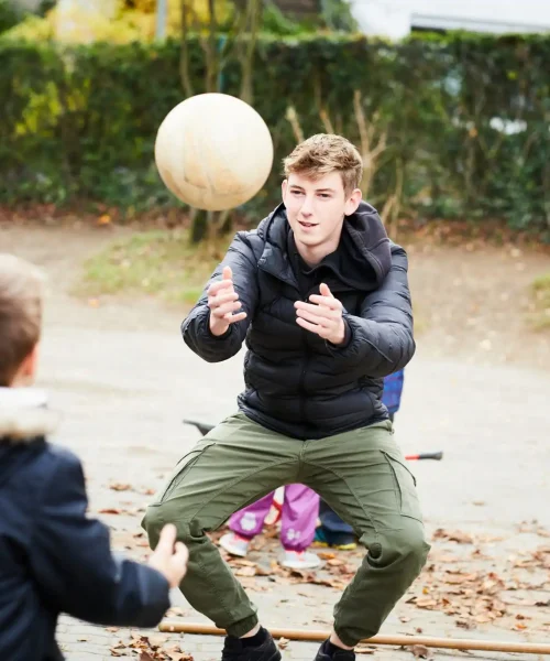 Jugendlicher spielt mit einem Kind Ball werfen