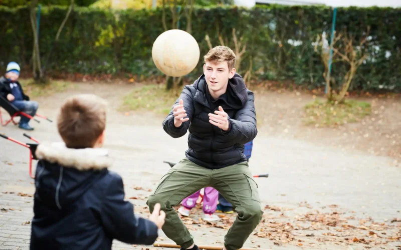 Jugendlicher spielt mit einem Kind Ball werfen