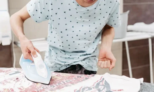 Junger Mann beim Bügeln von Klamotten