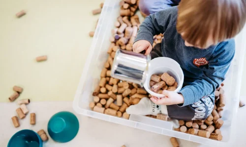 Kind spielt in einer Box mit Korken