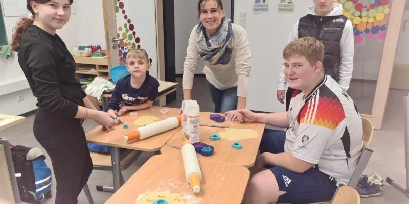 Kinder und Betreuer backen zusammen Kekse