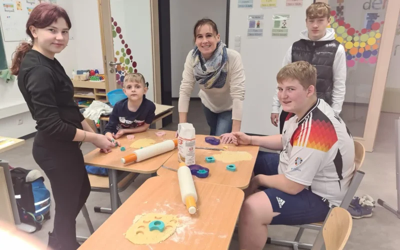 Kinder und Betreuer backen zusammen Kekse