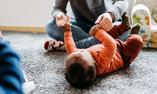 Lebenshelfer spielt mit einem Baby zusammen