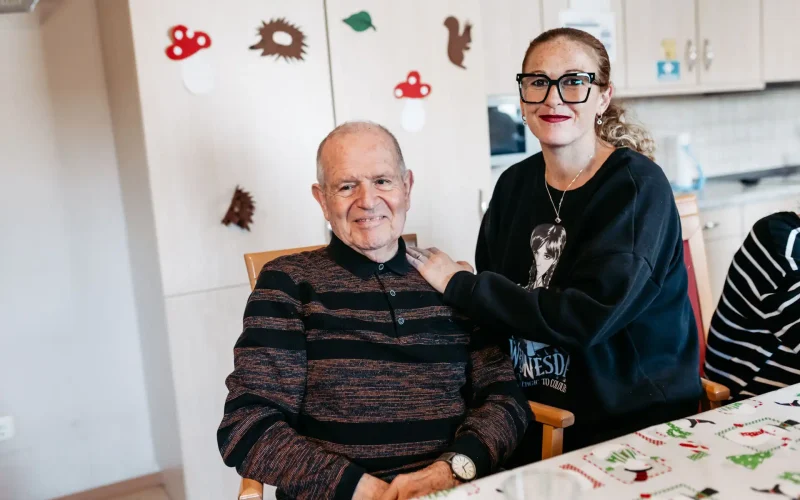 Lebenshelfer und Senior schauen glücklich in die Kamera