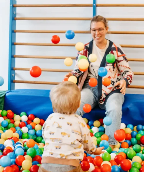 Lebenshelferin spielt mit einem Kindergartenkind im Bällebad