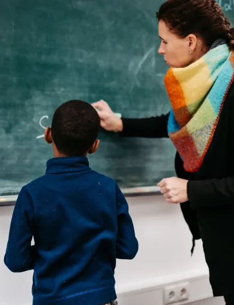 Lehrerin zeigt einem Schüler etwas an der Tafel