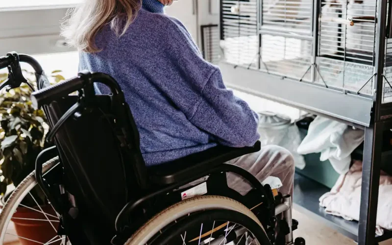 Seniorin im Rollstuhl vor einem Vogelkäfig